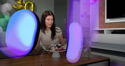 Seated woman cutting birthday cake at intimate home party with gold 30 balloons and decor