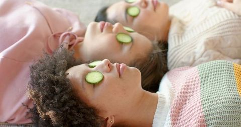 Diverse women relaxing with cucumber eye slices in cozy at-home spa and self-care moment