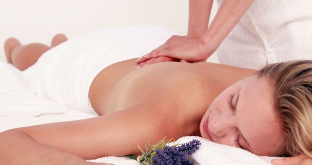 A Caucasian woman enjoys a relaxing massage in a serene spa environment, with copy space. Her peaceful expression underscores the tranquility and therapeutic nature of the treatment.