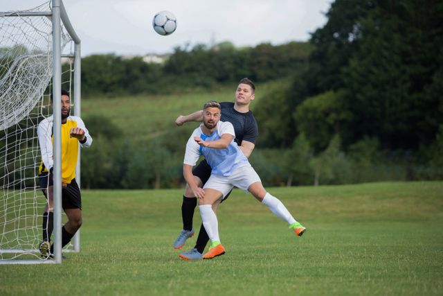 Football players are seen competing for the ball near the goal. This image is ideal for use in sports-related articles, blog posts, promotional materials for soccer events, and advertisements targeting soccer enthusiasts.