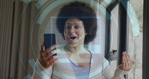 Black woman holding smartphone and gesturing at glass door with augmented reality hud