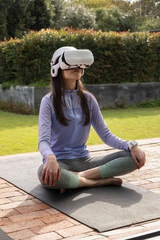 Teen practicing vr meditation on yoga mat in backyard for mindfulness and fitness