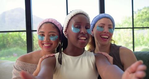 Three friends enjoying at-home spa night wearing under-eye patches and terry headbands