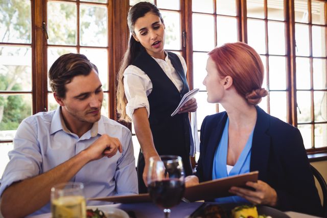 Business people discussing menu card with waitress in restaurant
