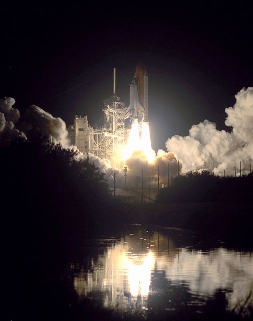Dramatic night shot of Space Shuttle Endeavor lifting off on November 30, 2000, with reflections in nearby waters. Ideal for use in educational material, articles on space exploration, NASA missions, and presentation on the STS-97 crew's mission to deliver and assemble the U.S. electrical power system onboard the ISS.