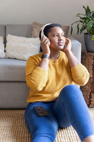 African american woman listening to music with headphones at home, cozy living room moment