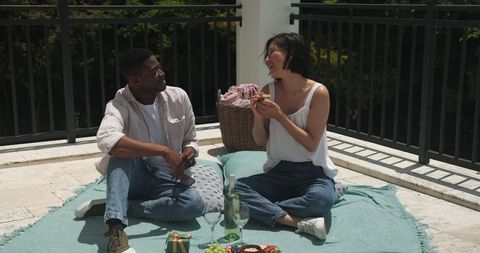 Couple enjoying picnic on balcony during sunny daytime