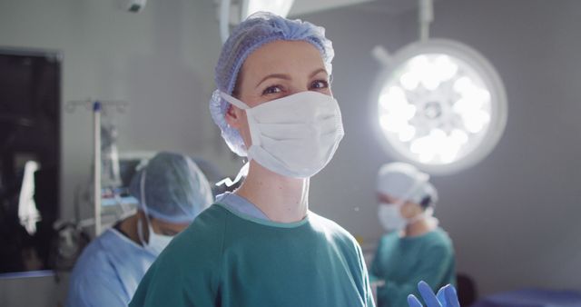 Surgeon smiling while wearing a mask and surgical cap in an operating room. Ideal for healthcare, medical profession, hospital, surgery, and healthcare marketing materials.