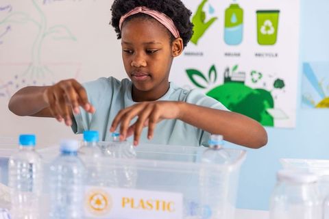 African american girl sorting plastic bottles in classroom recycling lesson for schools