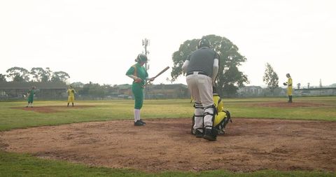 Female softball batter preparing to swing with umpire observing