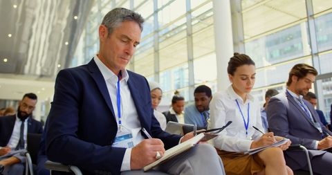 Diverse Professionals at Seminar Taking Notes