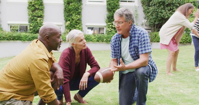 Image of happy diverse female and male senior friends playing american football in garden. retirement lifestyle, spending quality time with friends.