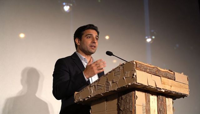Male speaker delivering keynote at sustainable cardboard lectern with gooseneck microphone