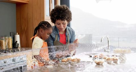 Mother and child decorating cupcakes on kitchen island, sharing warm baking moment