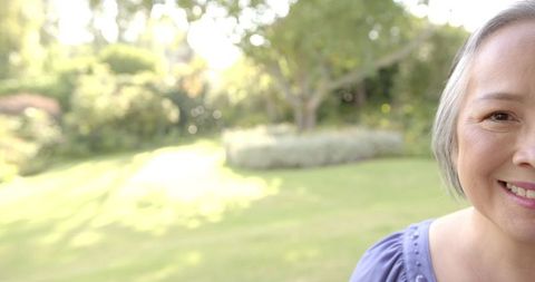 Happy Senior Asian Woman Enjoying Lush Green Garden