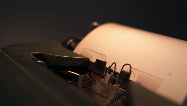 Vintage mechanical typewriter closeup blank page low-key lighting retro writing concept