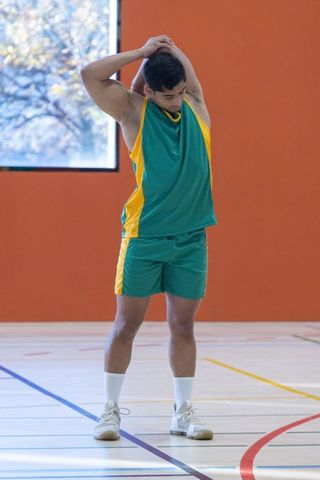 Male athlete stretching on indoor court for arm flexibility