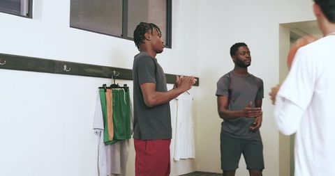 Locker room team clapping and talking before game holding basketball and jerseys