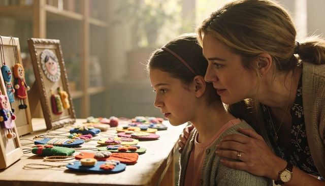 Mother and daughter examining colorful handmade felt ornaments in cozy craft workshop