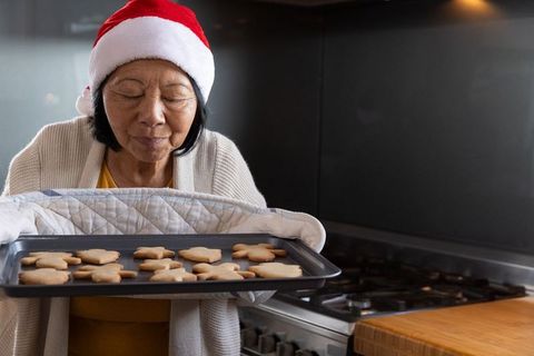 Senior Woman Smelling Freshly Baked Holiday Cookies in Kitchen