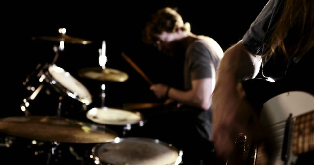 A young Caucasian male musician is playing the drums intensely, with copy space. His focus and the motion blur convey the energy and passion of a live music performance.