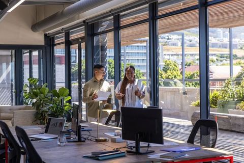 Diverse Coworkers Collaborating by Modern Office Windows