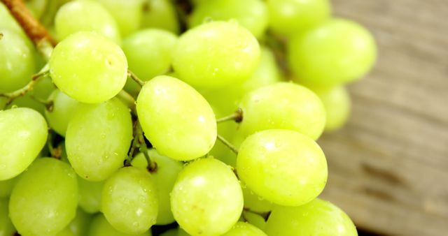 Close-up image of fresh green grapes with visible water droplets. Ideal for promoting healthy eating, organic produce, juicing recipes, and vitamin-rich diets. This visually appealing image can be used in food blogs, grocery store advertisements, and nutrition-based articles.