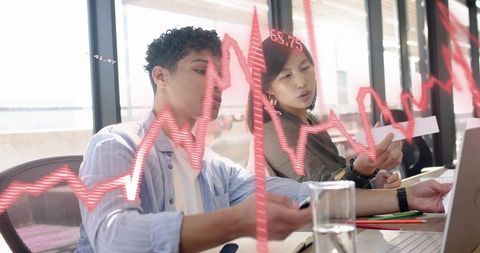 Young Professionals Collaborating and Analyzing Financial Data with Red Stock Chart Overlay