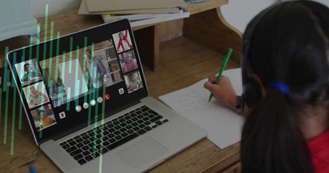 Student taking notes during live online class at home with laptop headset and notebook