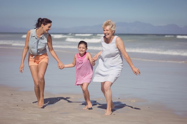 Three generations of women enjoying a sunny day at the beach, running and holding hands. Perfect for promoting family vacations, summer activities, and outdoor fun. Ideal for use in travel brochures, family-oriented advertisements, and lifestyle blogs.