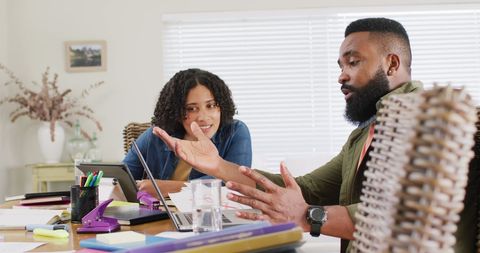 Diverse friends collaborating on project with laptop at home