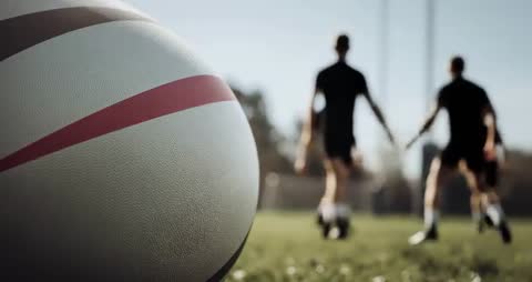 Close-up Rugby Ball with Dynamic Game Scene in Background