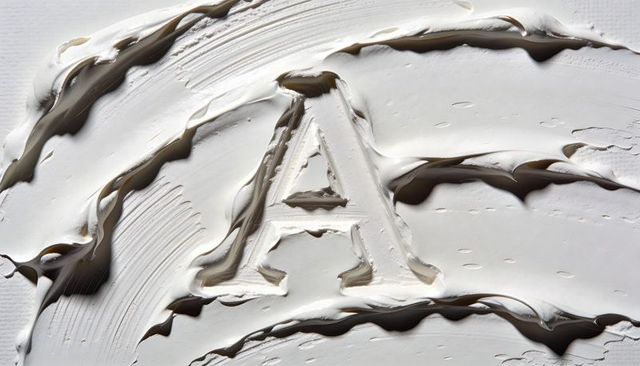 Capital letter a carving in thick white paint with impasto texture and brush smears macro