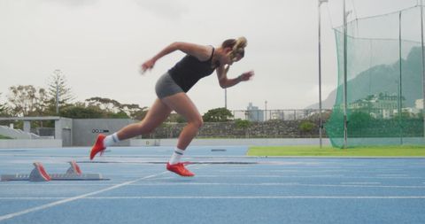 Female athlete sprinting from starting blocks on track