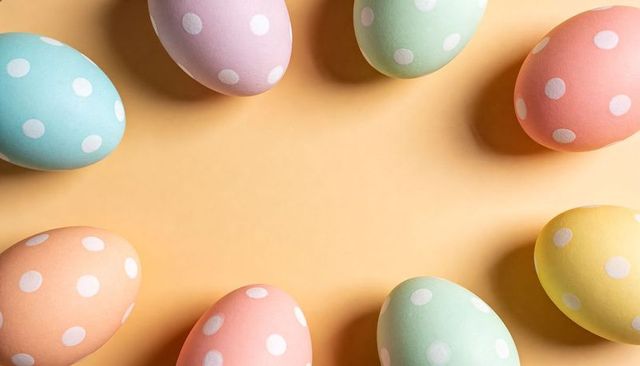 Pastel polka-dot easter eggs framing central copy space flatlay on peach pastel background