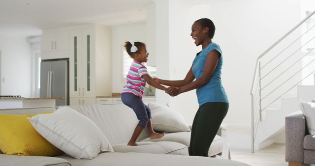 Happy african american mother and daughter dancing and having fun at home. staying at home in self isolation during quarantine lockdown.