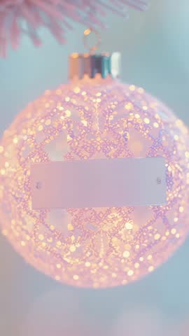 Hanging pink lace snowflake ornament glowing with warm LED lights vertical bokeh video