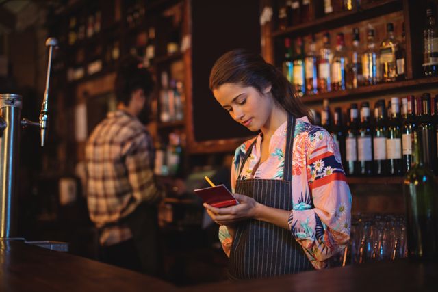 Waitress taking an order on notepad at counter in pub