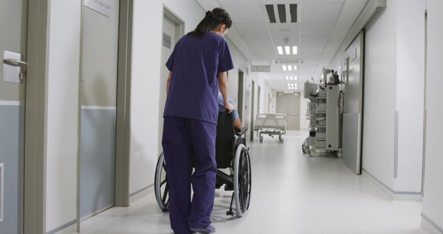 Nurse dressed in uniform assisting a patient in a wheelchair down a hospital corridor. The hallway is clean and well-lit, suggesting a professional medical environment. This image can be used for healthcare and medical-related content, patient care brochures, hospital websites, or promotional material for caregiving services.