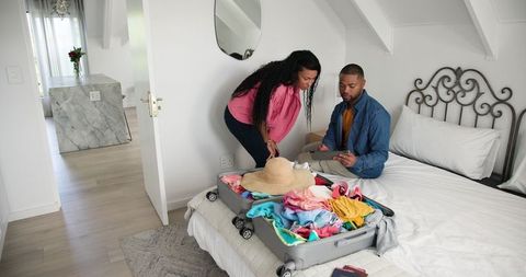 Happy Couple Packing Suitcase for Holiday in Relaxing Home Setting