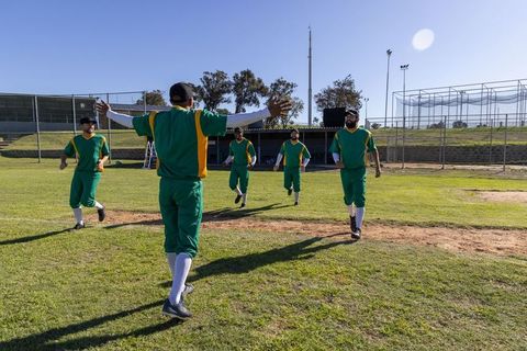 Baseball teammates celebrating run, running from outfield, leader welcoming, arms outstretched
