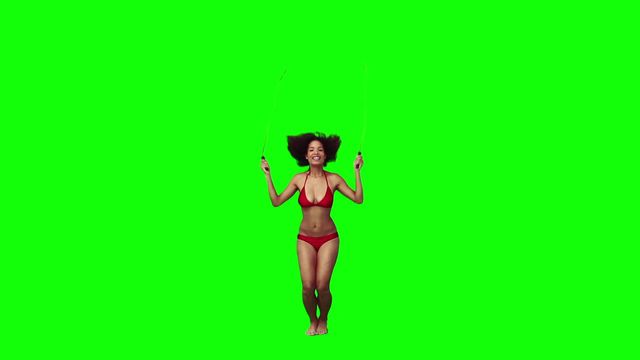 Woman in a bikini is using a skipping rope against a green screen background. This video is perfect for fitness blogs, workout videos, health and wellness websites, or any project requiring a cut-out or fully customizable athletic model.