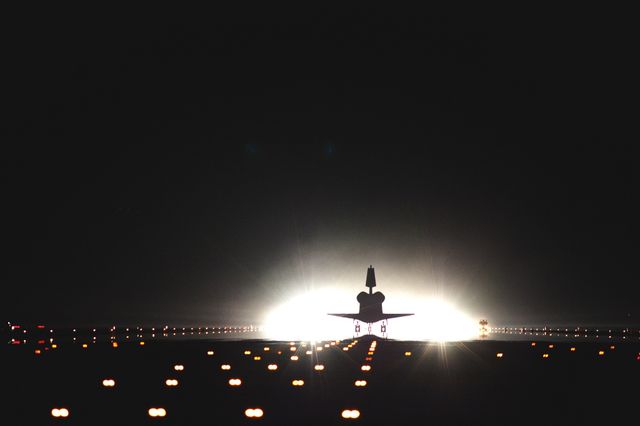 Image depicts space shuttle landing on illuminated runway at night. Ideal for concepts involving space exploration, aviation technology, and nighttime operations. Suitable for use in articles about aerospace advancements, educational materials, and promotional content for space and aviation organizations.