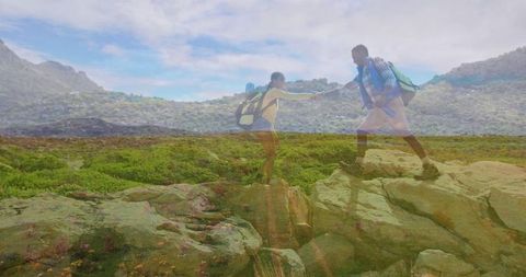 Hikers Supporting Each Other on Rocky Terrain in Scenic Mountains