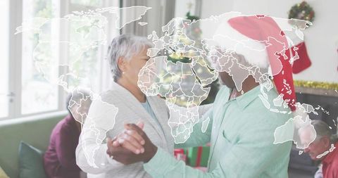 Dancing senior couple celebrating holiday gathering wearing santa hat in cozy living room