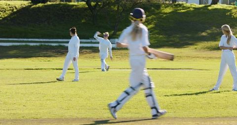 Women Practicing Cricket on Sunny Field