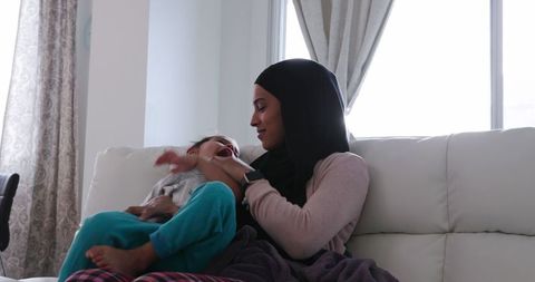 Mother in Hijab Bonding with Daughter on Sofa