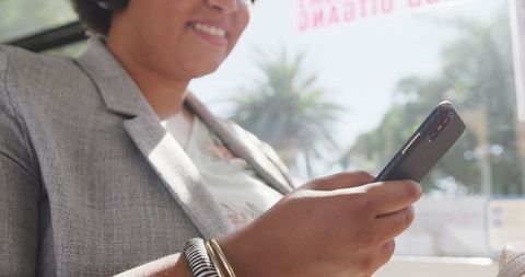 Happy plus size biracial woman using smartphone on bus ride