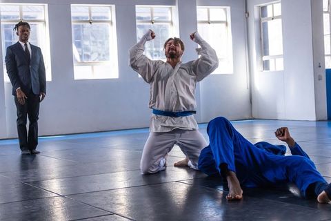 Martial Artist Celebrating Victory on Tatami with Spectators