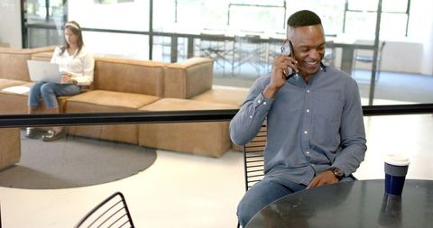 Smiling man enjoying phone call during office coffee break